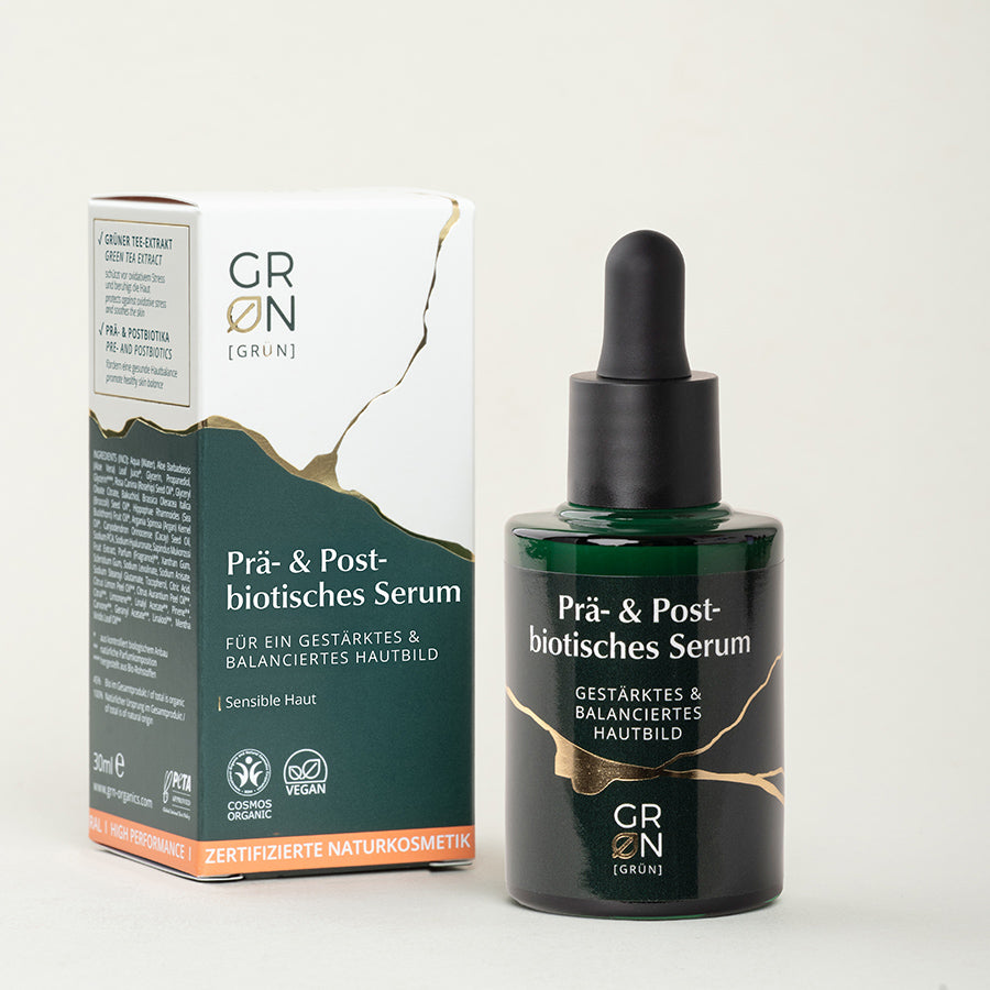 Flasche des prä- & postbiotischen Serums mit Pappumverpackung, enthält grünen Tee-Extrakt, Lactobacillus Ferment, Inulin, Cacay-Öl und Bio-Jojobaöl; pflegt, stärkt die Hautbarriere und sorgt für geschmeidige, beruhigte Haut